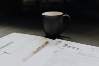coffee mug near open folder with tax withholding paper by Kelly Sikkema courtesy of Unsplash.